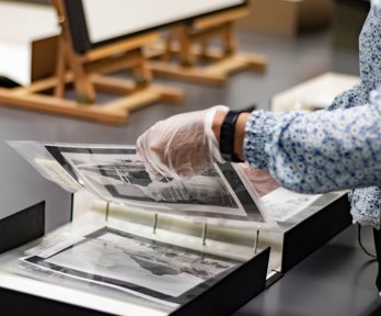 A researcher wearing archival gloves viewing historic photographs in a folder