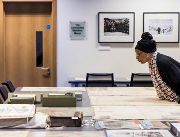 A woman looking at historic materials, including maps, books, and photographs