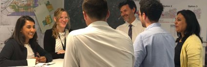 Six professionals standing around a table having a discussion