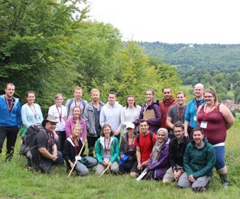 A group of trainee teachers gathered together in the outdoors during a fieldwork day, all smiling and holding geography fieldwork equipment