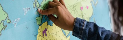 A child is pointing to the UK on a map of the world