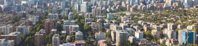 A birds eye view of Santiago, Chile. tall apartment blocks, skyscrapers and trees litter the landscape.