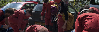 People wearing red caving gear and preparing for a descent