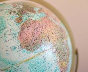 A pale blue globe showing the continent of Africa in pinks and greens.