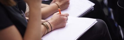 Seated people taking notes using notebooks