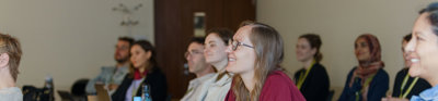 A group of people sit in a seminar room at the RGS-IBG Annual Conference. They are listening to a discussion, some of them are smiling.