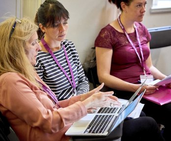 Two women having a conversation while using a laptop