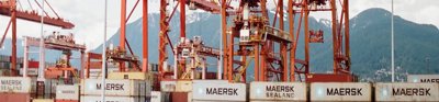 Shipping containers on a boat, with red cranes at the side ready to lift them on and off. 