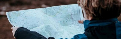 A young boy in the outdoors holding a map