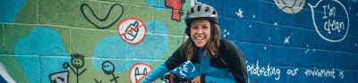 Franke Dewar next to bike pointing at wall mural about the environment