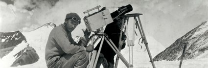 Historic black and white photograph of two men taking photographs in a snowy mountainous environment