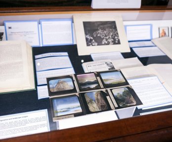 Display of historic materials from Royal Geographical Society collections, including books, printed labels, and glass lantern slides