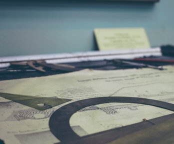 Mathematical equipment laying on top of some scale drawing plans