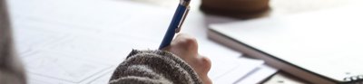 A person writing at a desk 