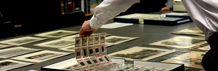 A researcher looking at sheets of historic photographic negatives