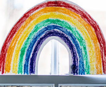 A drawn image of a rainbow, placed in a window.