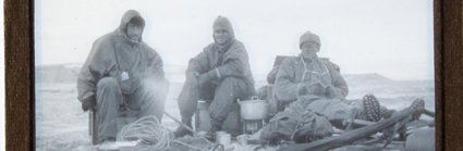 Historic black and white lantern slide showing three men wearing expedition clothing and with expedition equipment