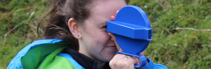 Girl in a blue coat using equipment to do geography fieldwork