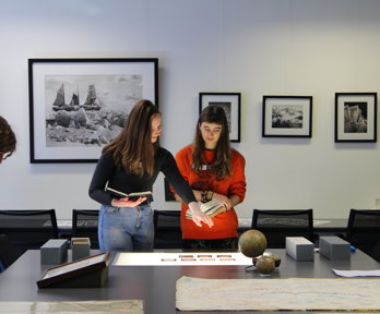 Two women beside a table looking at slides laid on a lightbox.